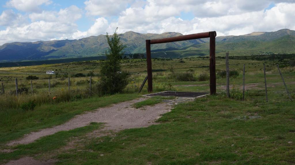 een onverharde weg in een veld met een hek en bergen bij Los Chañaritos in La Cumbre