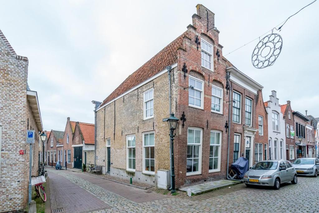 une rue avec des bâtiments en briques et des voitures garées dans une rue dans l'établissement Pakhuis de Venkel, à Zierikzee