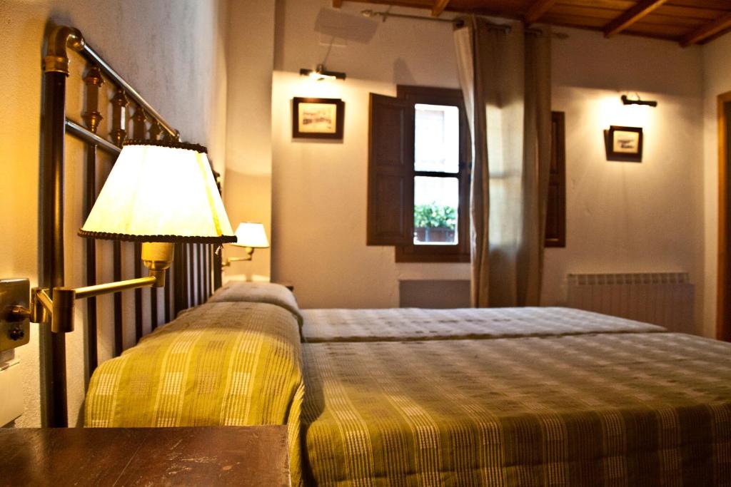 ガータにあるCasa Rural Las Jañonasのベッドルーム1室(ベッド1台、ランプ、窓付)