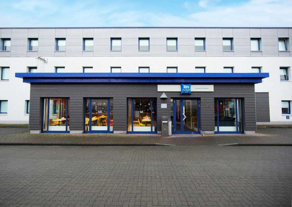 een gebouw met een winkel met glazen ramen bij ibis budget Flensburg Handewitt in Handewitt