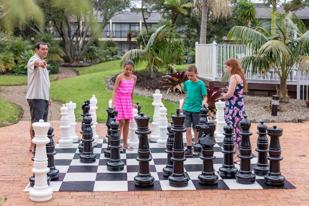 a family playing chess on a giant chessboard at Holiday Inn Auckland Airport by IHG in Auckland