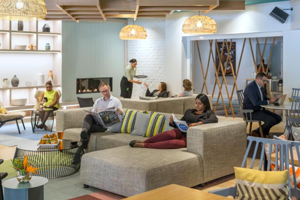 a group of people sitting on couches in a living room at Holiday Inn Auckland Airport by IHG in Auckland