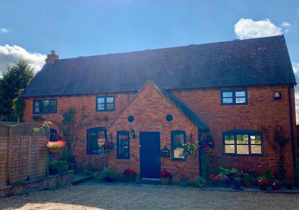 a red brick house with a blue door at Catesby Barn Farm B&B in Daventry