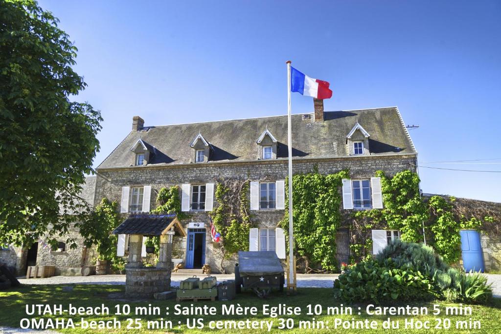 una grande casa in pietra con una bandiera canadese sopra di Domaine Airborne ad Angoville-au-Plain