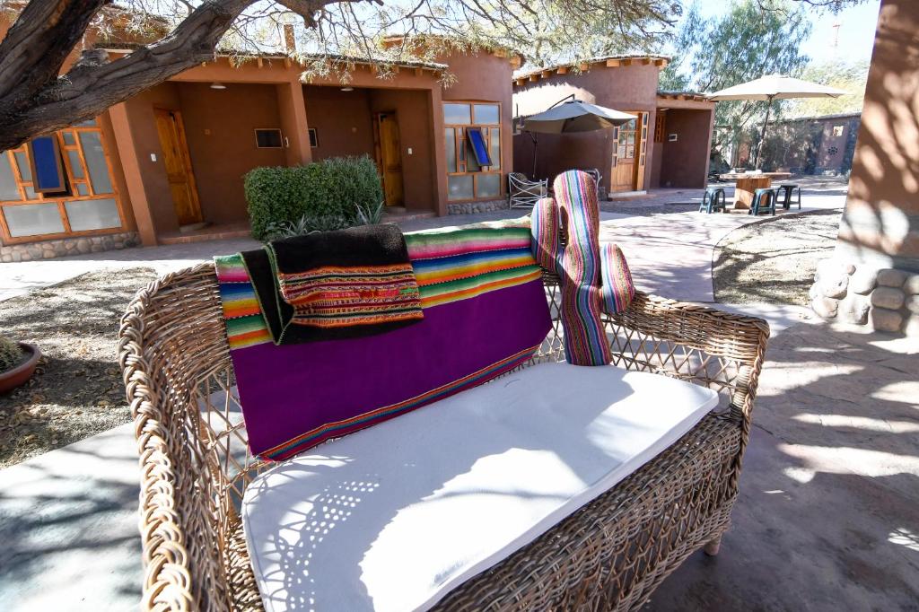 a wicker bench with a colorful blanket on it at Hostal y Cabañas Renta House San Pedro in San Pedro de Atacama