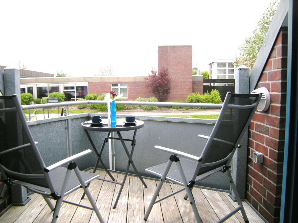 d'une terrasse avec 2 chaises et une table sur un balcon. dans l'établissement Nordseeinsel, à Horumersiel
