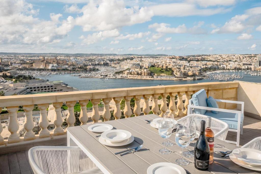 a table with plates and wine glasses on a balcony at Valletta Hastings Suites in Valletta
