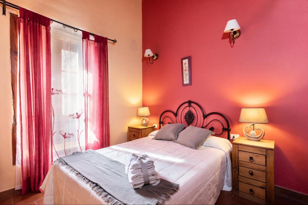 un dormitorio con paredes rosas y una cama con zapatos. en Casa Rural La Pestilla 1, en El Pinar de El Hierro