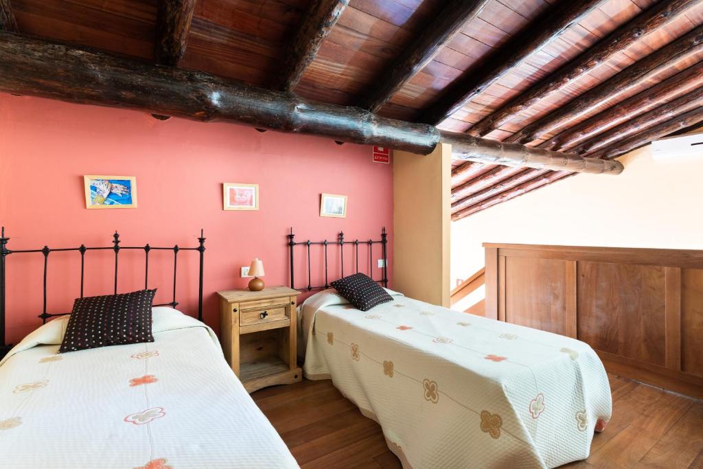 2 camas en una habitación con paredes rojas y techos de madera en Home2Book Charming Rustic House El Pinar & Wifi, en El Pinar de El Hierro