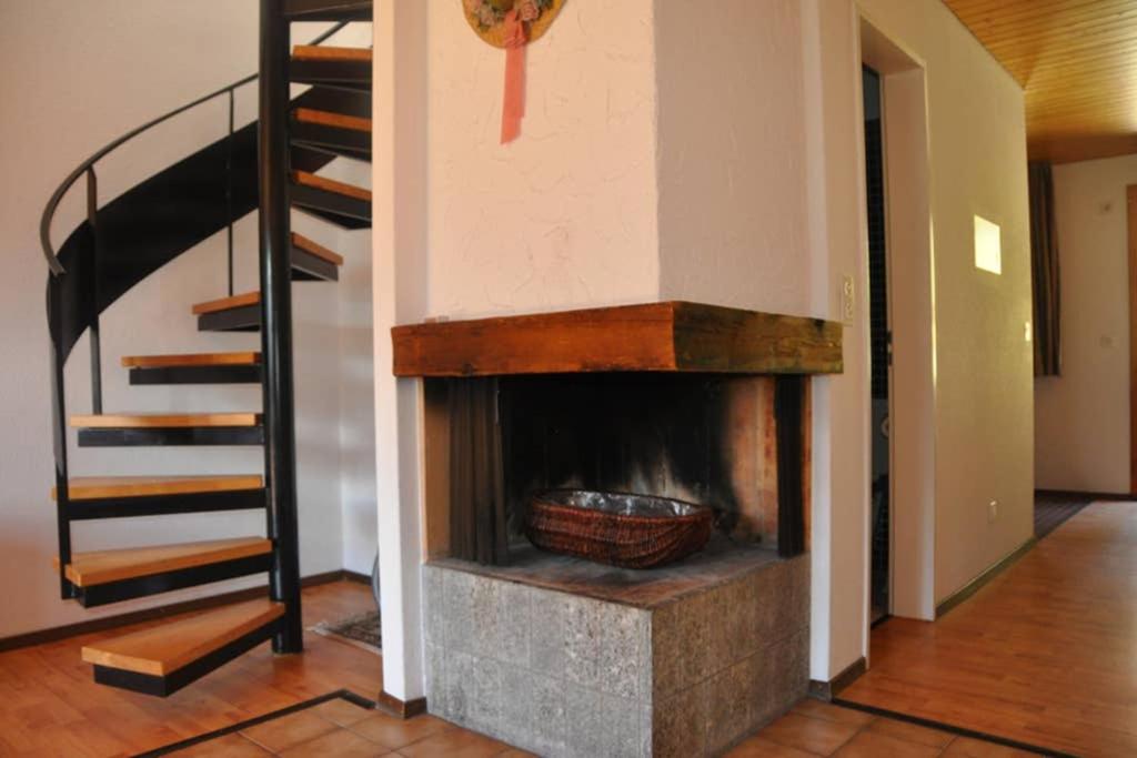 a fireplace in a living room with a spiral staircase at Chalet-Schümli Maisonette in Ernen