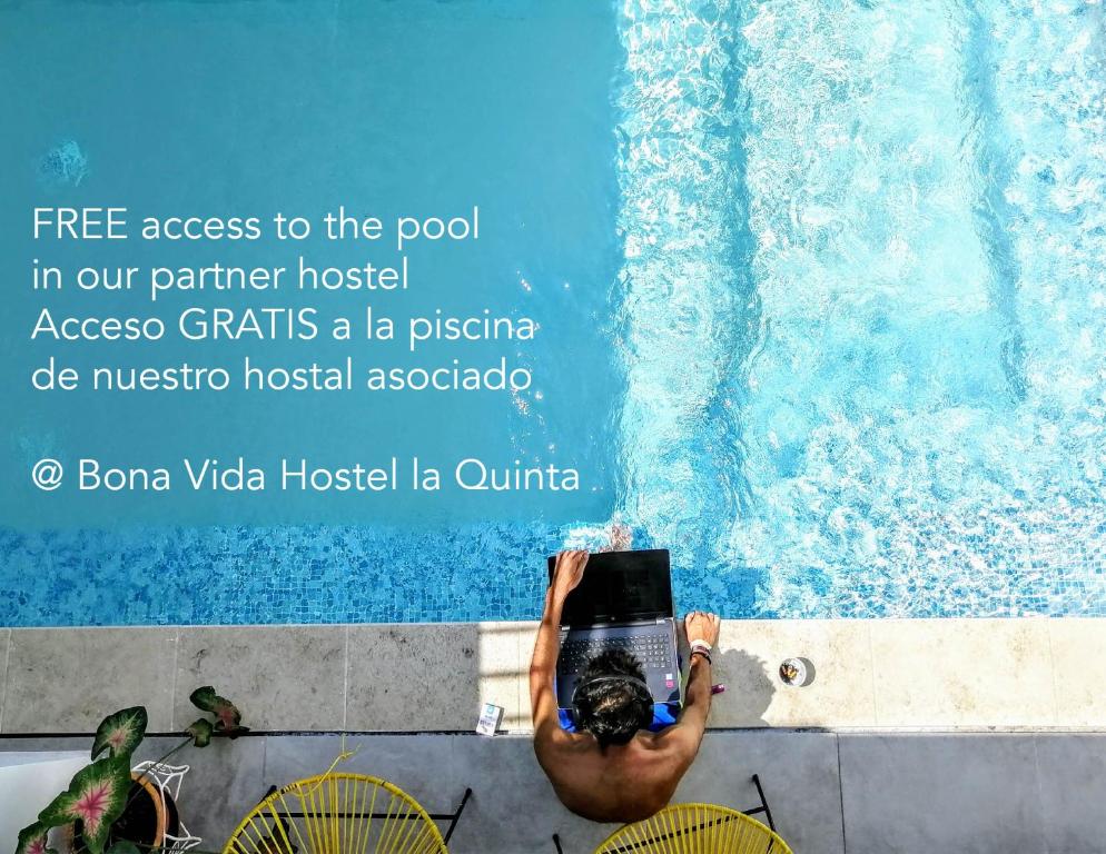 a man sitting in a chair in front of a swimming pool at Bona Vida Hotel in Ríohacha