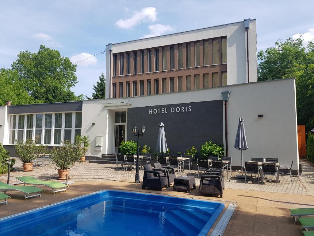 a hotel building with a pool and chairs and umbrellas at Doris Hotel in Siófok