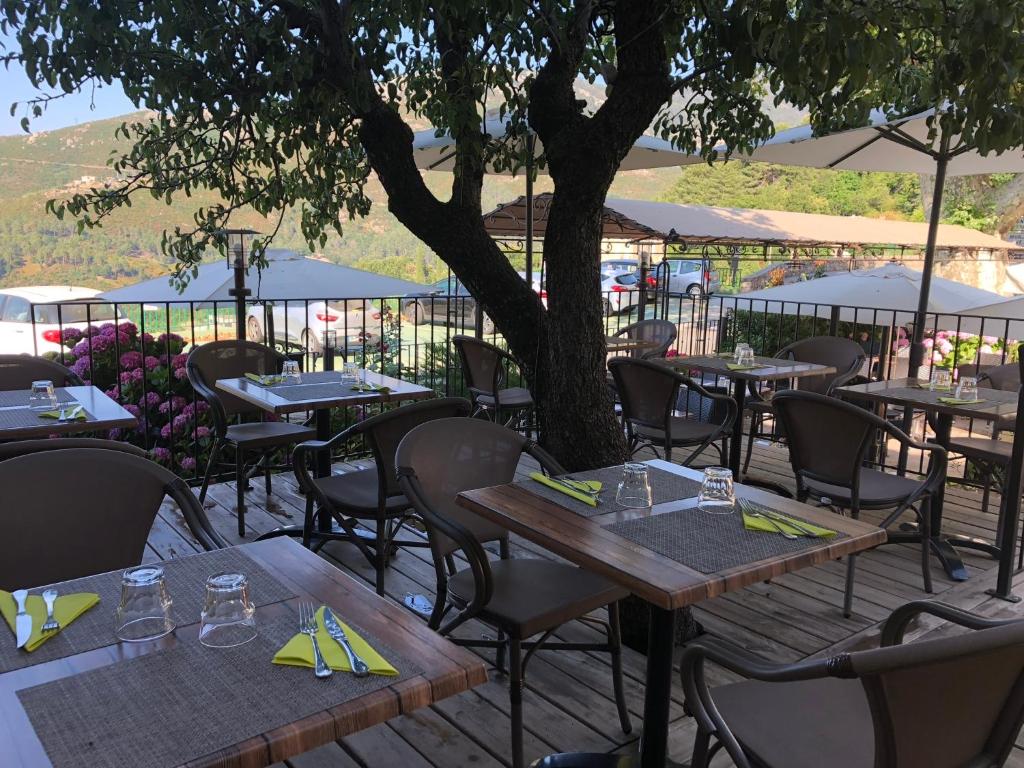 an outdoor restaurant with tables and chairs and a tree at Hotel U Campanile in Vivario