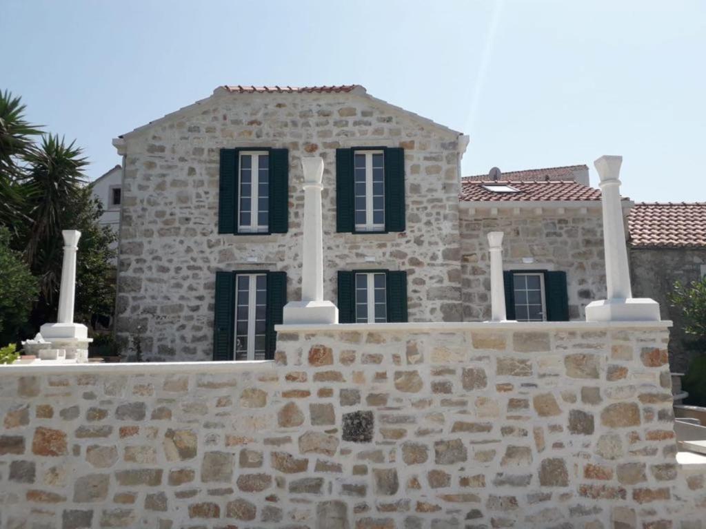 Casa de piedra con ventanas negras y pared de piedra en House Zemina, en Lumbarda
