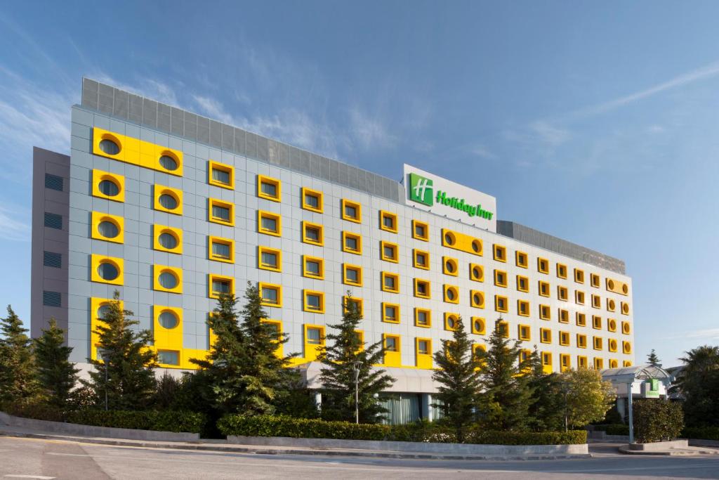 アテネにあるHoliday Inn Athens Attica Av, Airport W., an IHG Hotelの緑の看板が立つ高い白い建物