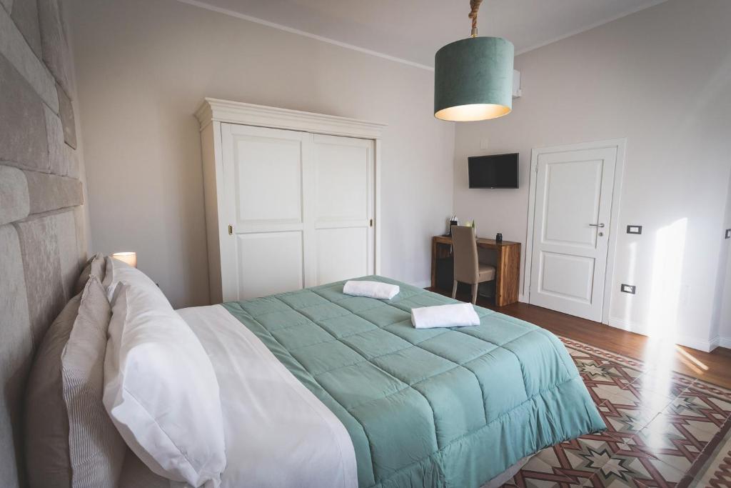 a bedroom with a bed with a green blanket at Piazza Duomo Deluxe in Cecina