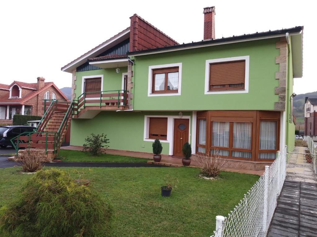 een groen huis met een hek ervoor bij Casa Con Jardin in Pomaluengo