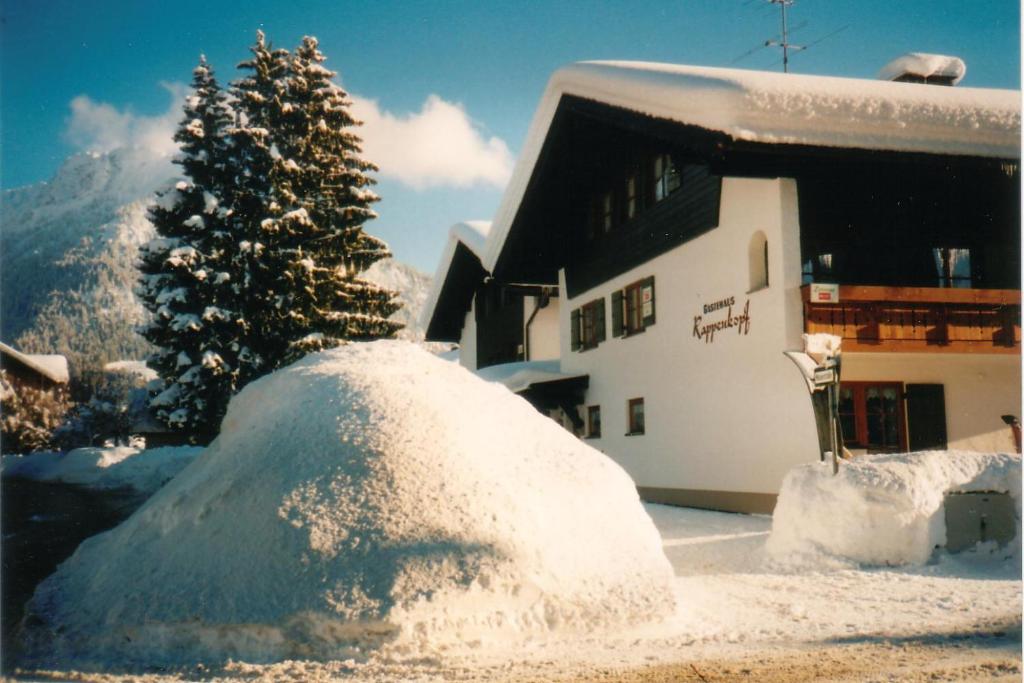 a pile of snow next to a building with a tree at Gästehaus Rappenkopf in Oberstdorf