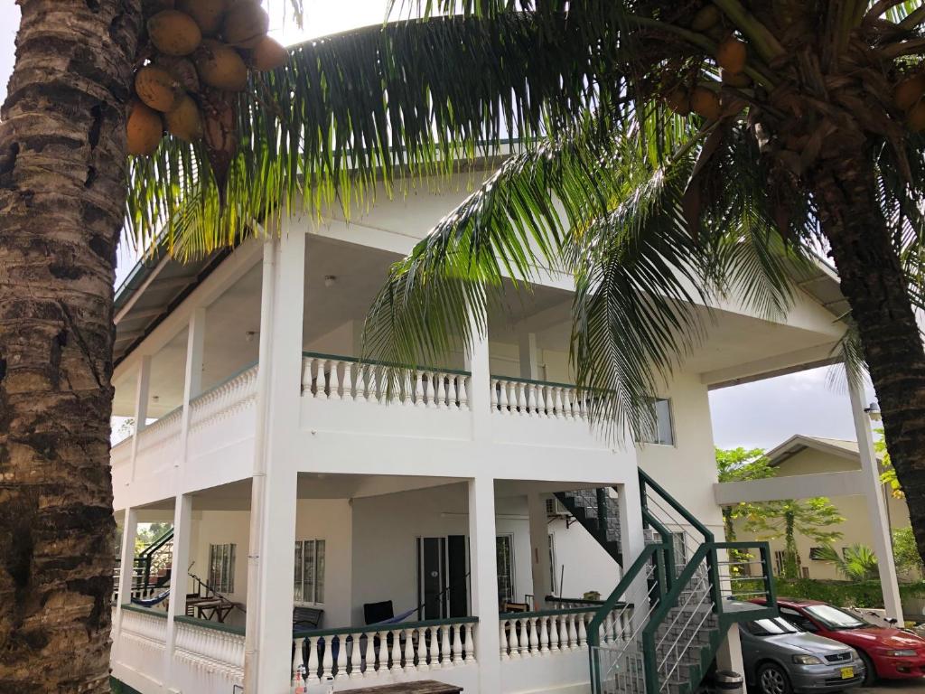una casa blanca con una palmera delante de ella en Greenheart appartment maximaal 3 pers 3 bedrooms 3 bathrooms, en Paramaribo
