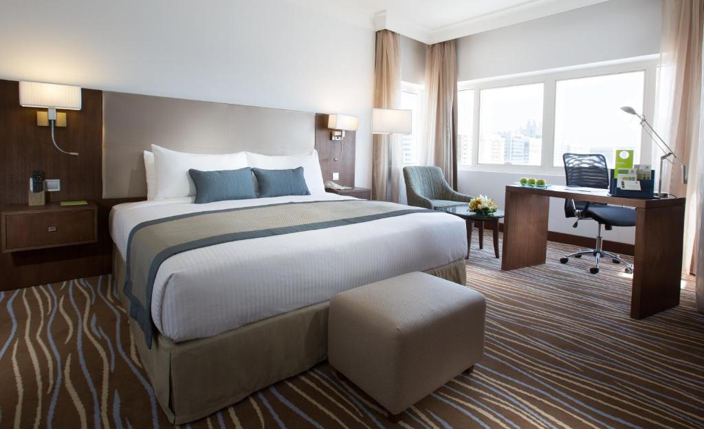 アブダビにあるCopthorne Downtown by Millenniumの大きなベッドとデスクが備わるホテルルームです。
