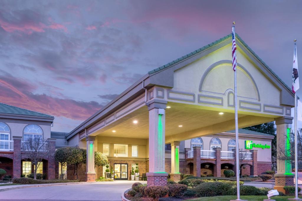 um grande edifício com uma bandeira em frente em Holiday Inn Auburn, an IHG Hotel em Auburn