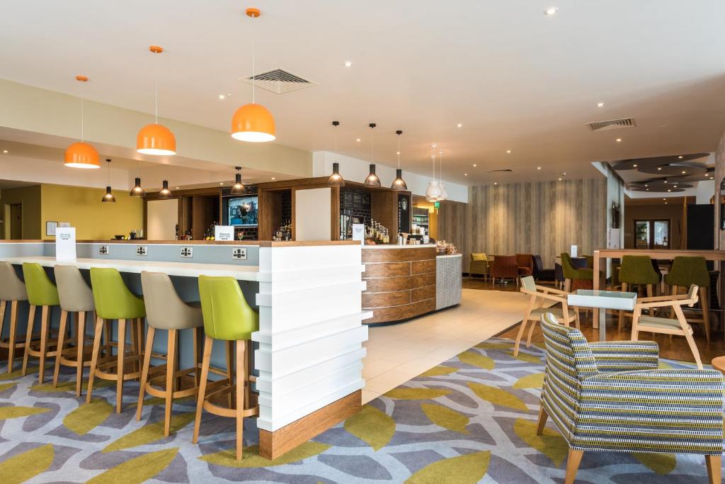 a hotel lobby with a bar and chairs at Holiday Inn Brighton Seafront by IHG in Brighton & Hove