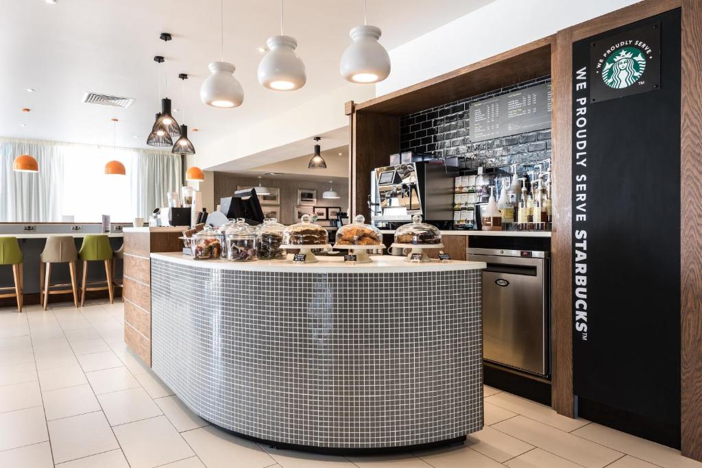 a restaurant with a counter with aasteryasteryasteryasteryasteryasteryasteryasteryastery at Holiday Inn Brighton Seafront by IHG in Brighton & Hove