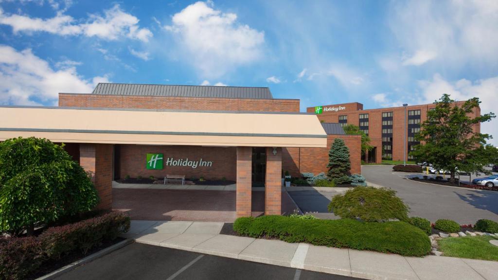 Holiday Inn Cincinnati Airport, an IHG Hotel في إيرلانغر: مبنى مع علامة نزل هيلتون في موقف للسيارات