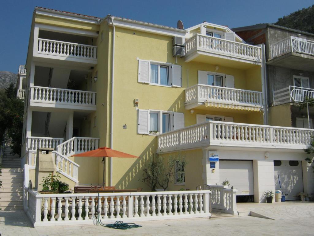 a yellow apartment building with white balconies on it at Apartments Villa Novak in Slano