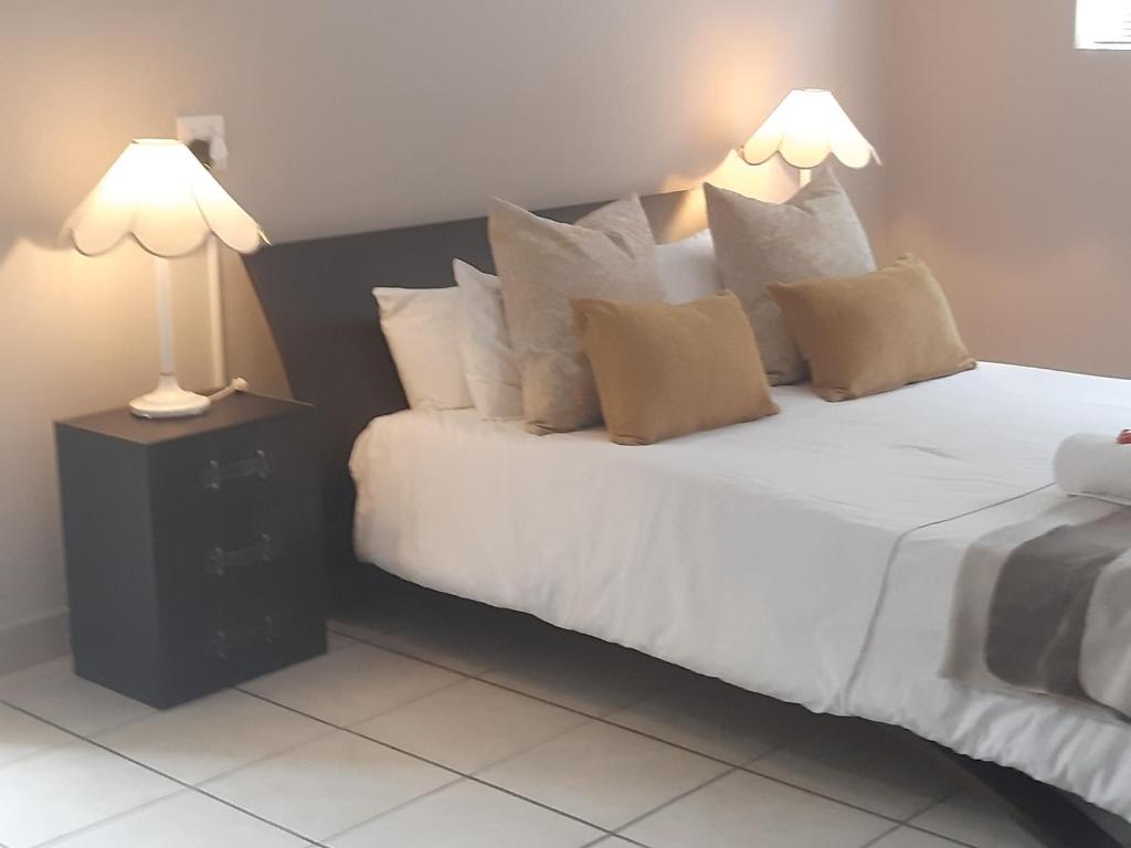 a bedroom with a large white bed with two lamps at Zeezicht Holiday Guest Unit in Franskraal