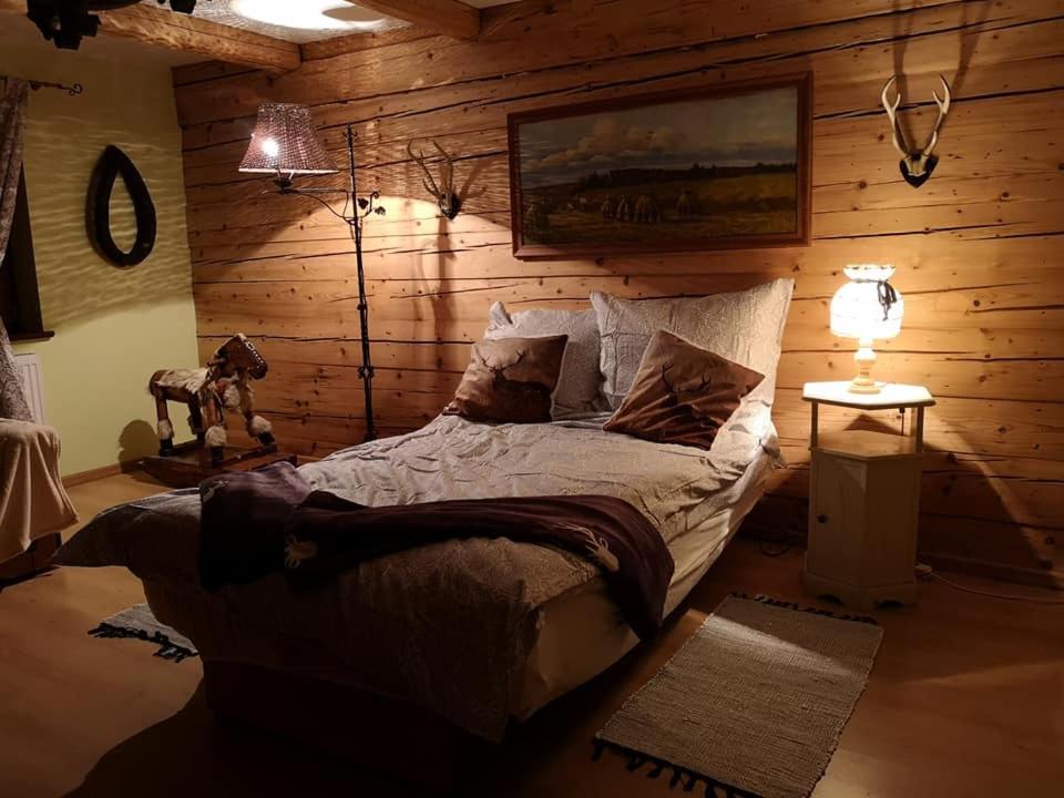 1 dormitorio con 1 cama en una pared de madera en Leśniczówka, en Jelenia Góra-Jagniątków