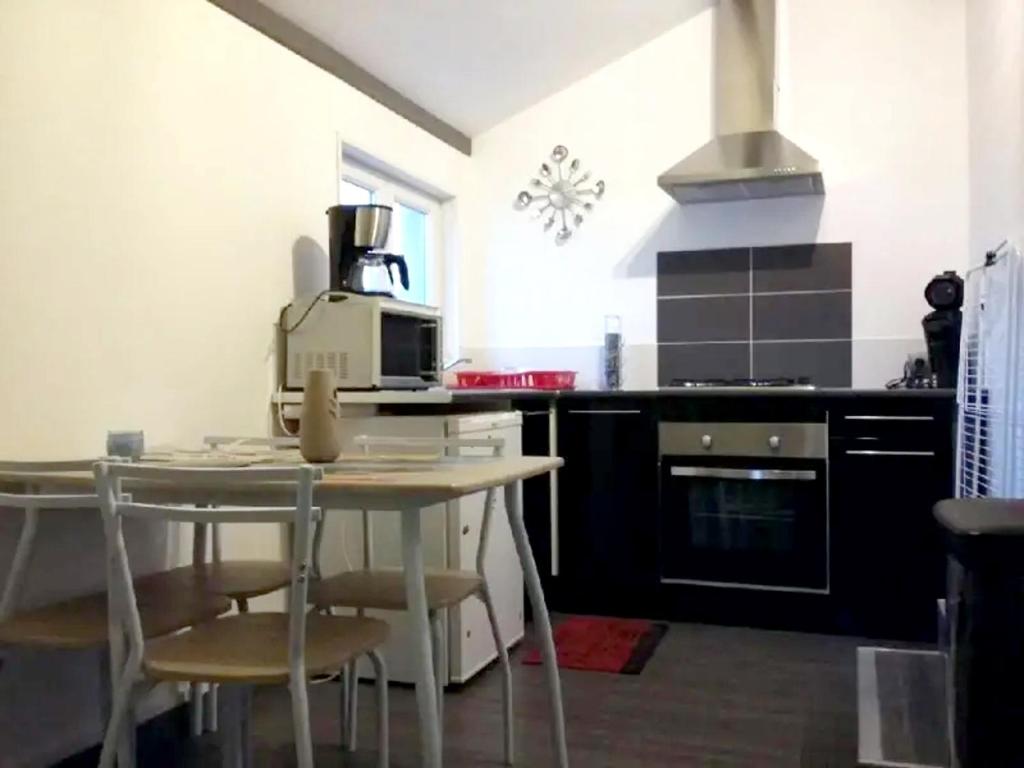 uma cozinha com uma mesa com cadeiras e um micro-ondas em Studio avec jardin clos et wifi a Vierville sur Mer em Vierville-sur-Mer