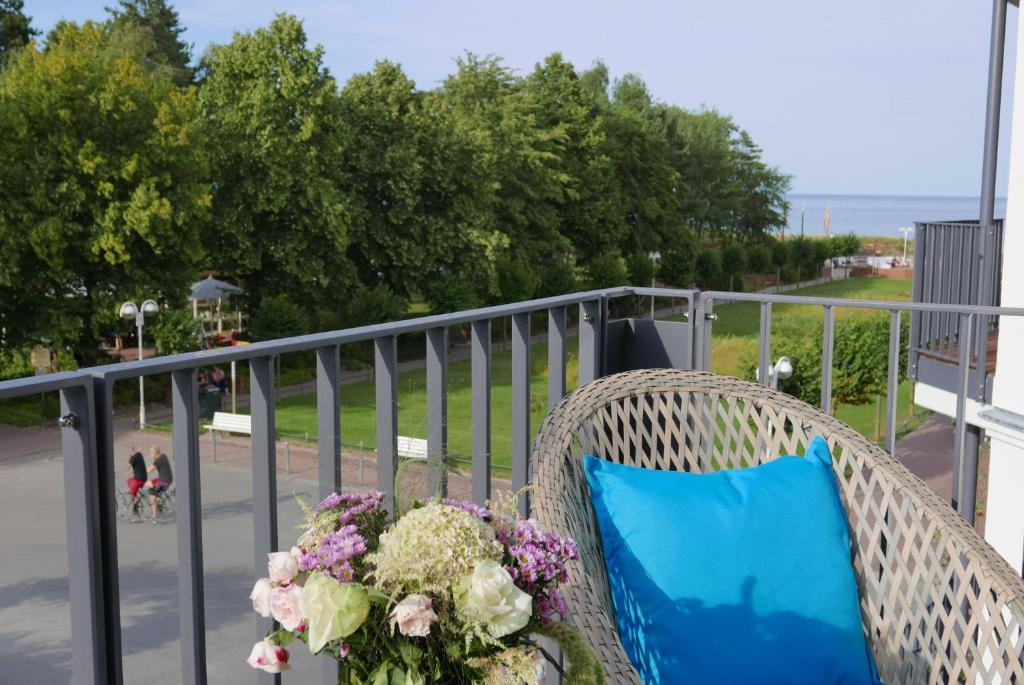 a wicker chair with a blue pillow and flowers on a balcony at Baabe Villen Ensemble FeWo 11 Blau in Baabe