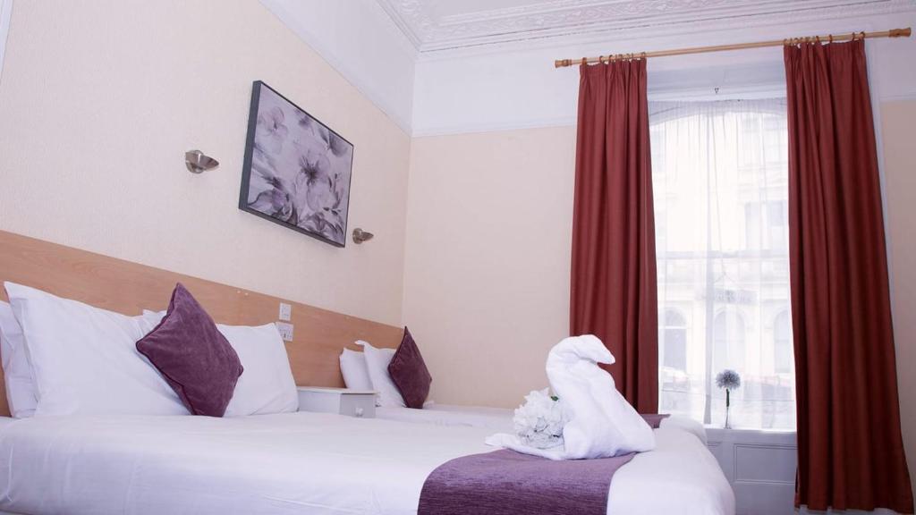 ein Hotelzimmer mit 2 Betten und einem ausgestopften Tier auf dem Bett in der Unterkunft The Retreat Guest House on Plymouth Hoe in Plymouth