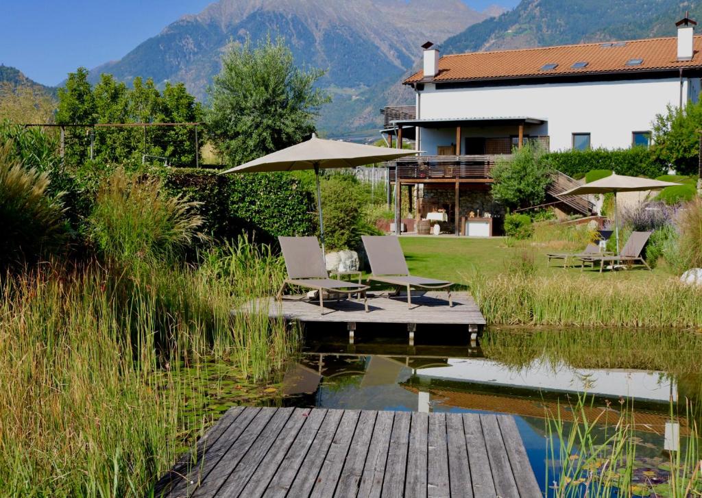 una casa con sillas y una sombrilla sobre un estanque en Gapphof, en Lagundo