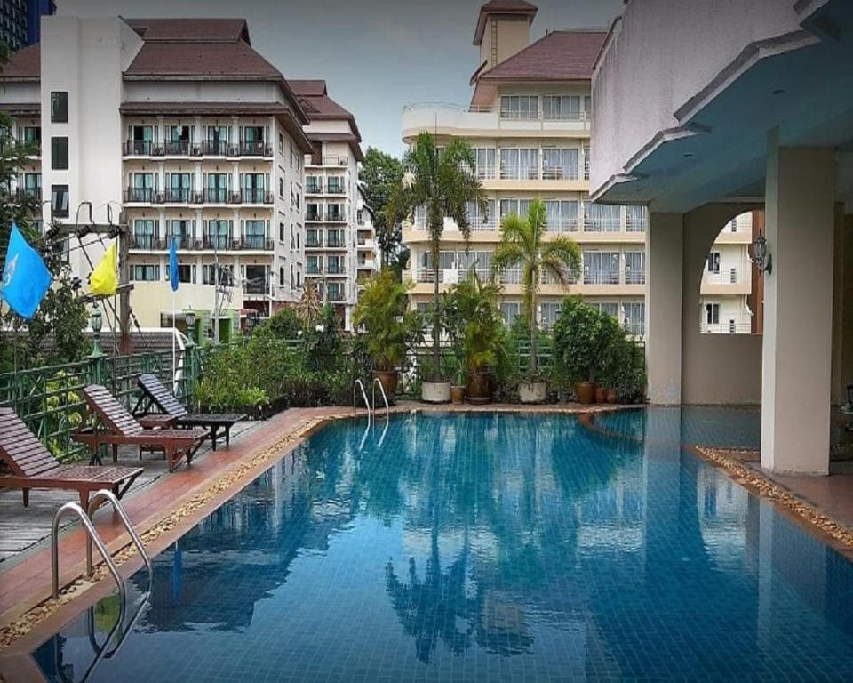 a large swimming pool with chairs and a building at Mike Beach Resort in Pattaya