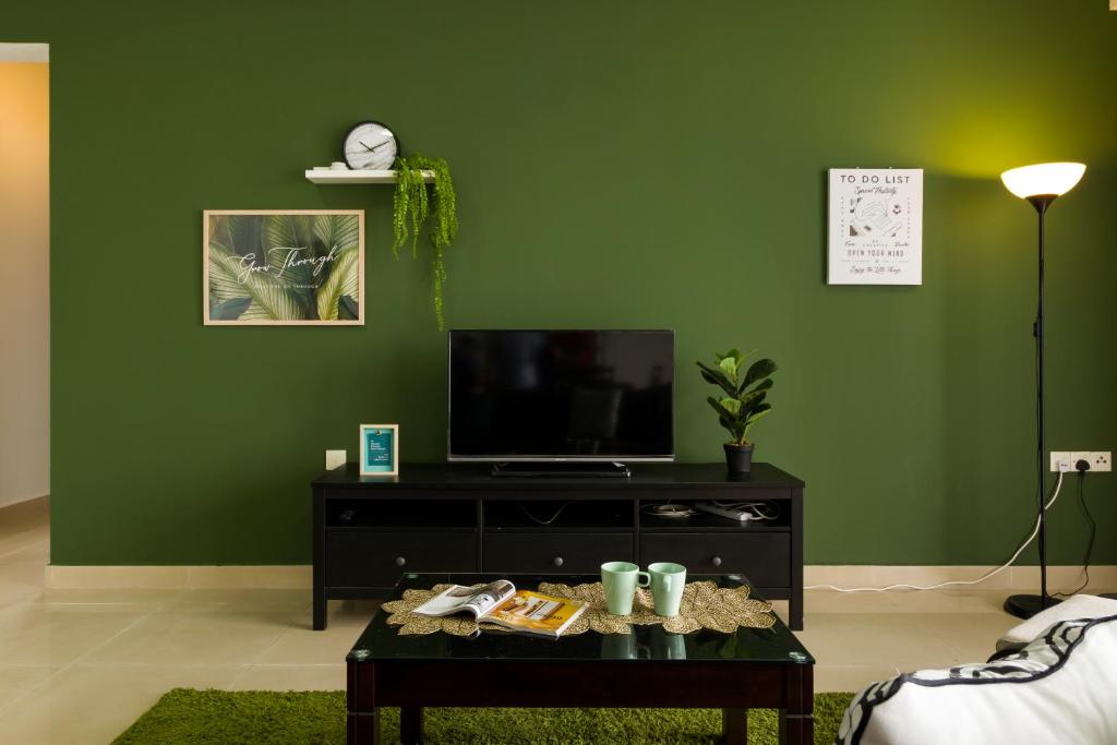 a living room with a tv and a green wall at PJ8 Service Suites by Airhost in Petaling Jaya