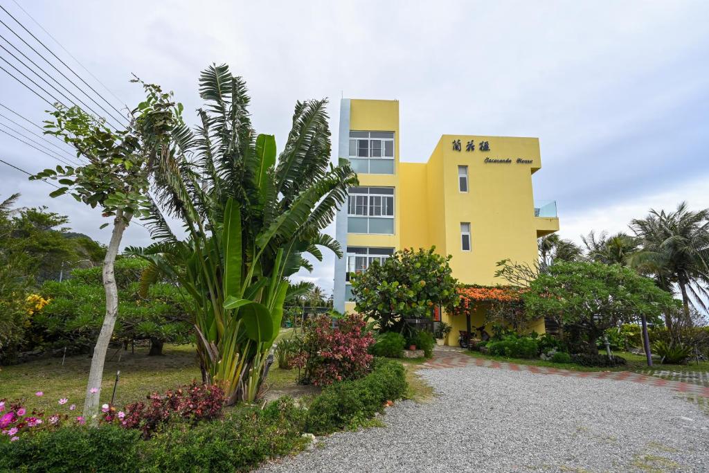 un bâtiment jaune avec des plantes devant lui dans l'établissement Jacaranda House, à Donghe