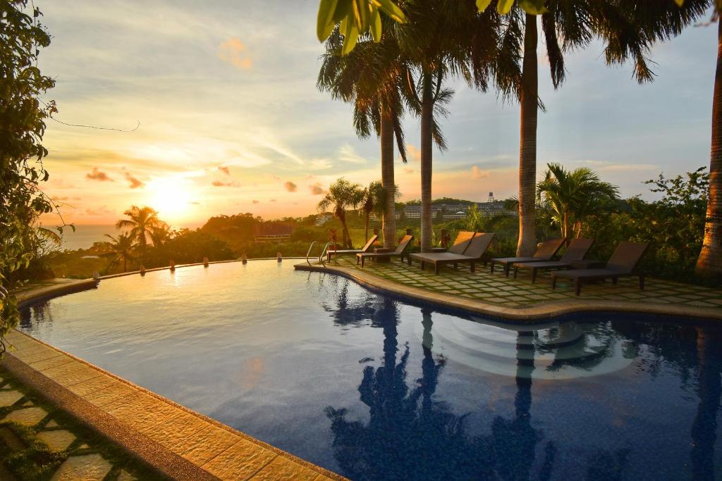 a pool with chairs and palm trees and the sunset at Hotel Soffia in Boracay