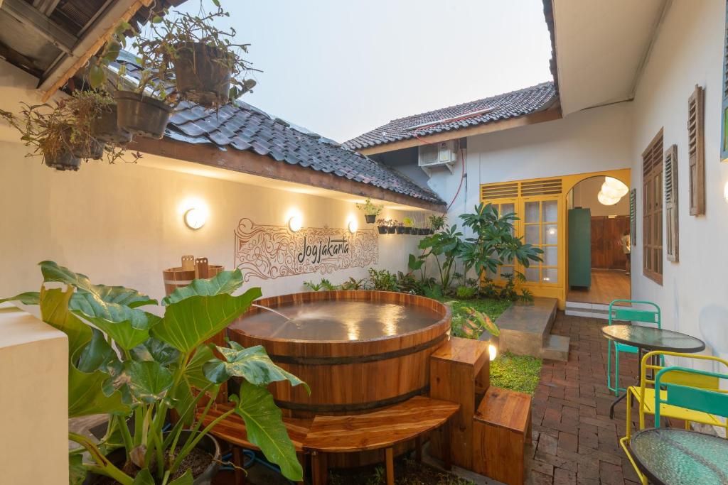 a patio with a hot tub and tables and plants at Wonderloft Hostel Jogja in Yogyakarta