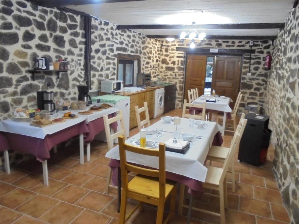 uma sala de jantar com duas mesas e cadeiras e paredes de pedra em Albergue Areitz Soroa em Arce