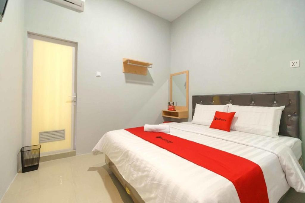 1 dormitorio con 1 cama grande con manta roja en RedDoorz @ Helvetia Medan 2, en Pulauberayan