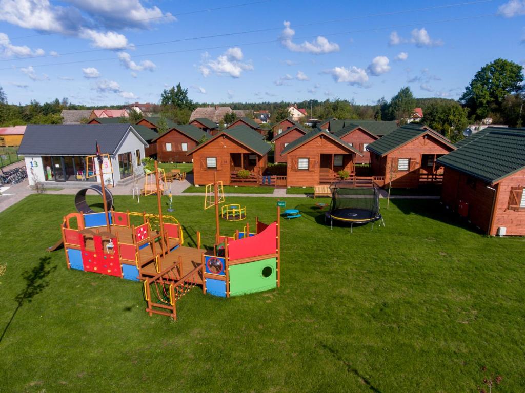 a yard with a playground with houses in the background at WICIE Domki na Polanie in Wicie