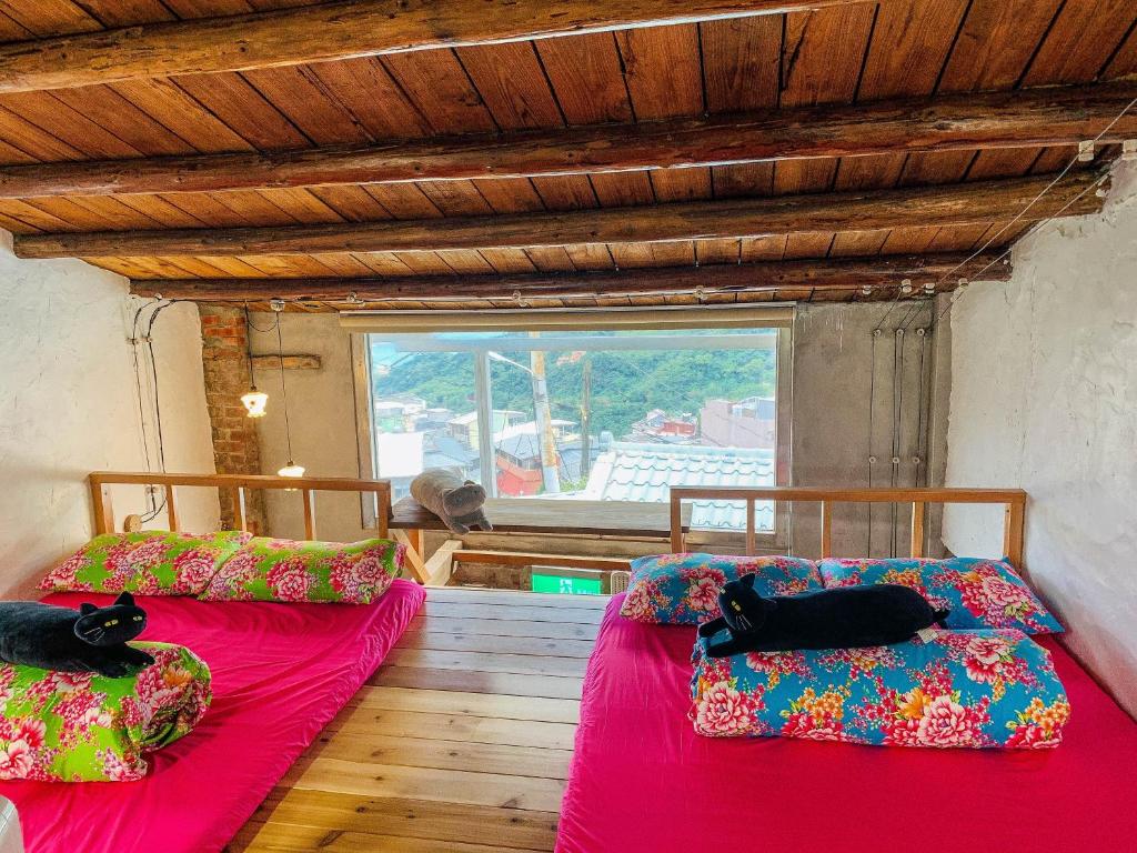 two beds in a room with a window at Jiufen Xiaomei Meow Seaview Homestay in Jiufen