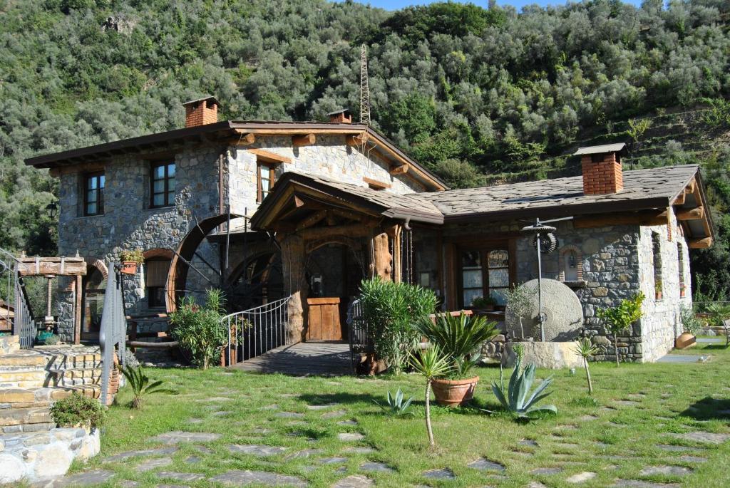 une maison en pierre avec une montagne en arrière-plan dans l'établissement Le Macine Del Confluente, à Badalucco