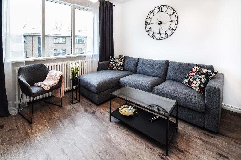 een woonkamer met een bank en een klok aan de muur bij Greenkey Apartment S30 in Reykjavík