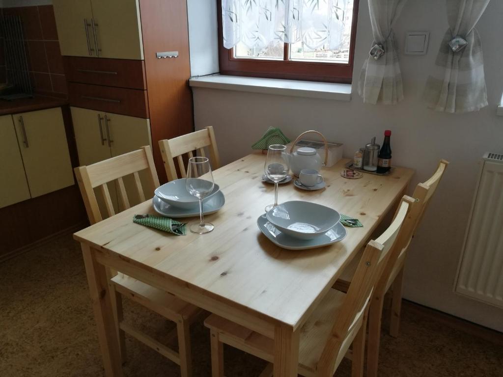 a wooden table with plates and wine glasses on it at Apartmán Mocca in Kašperské Hory