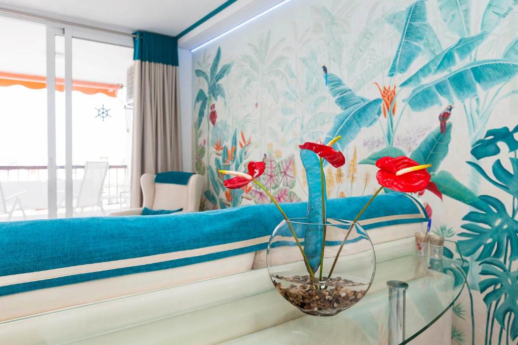 a bedroom with a bed and a vase with red flowers at First line sea, luxury penthouse, sea and sunset view Vivenda Vacational Guayero 618 in Los Cristianos