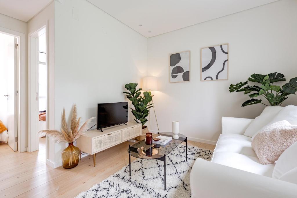 a white living room with a white couch and a tv at Casa Boma Lisboa - Modern & Luminous Apartment with Balcony - Alcantara I in Lisbon