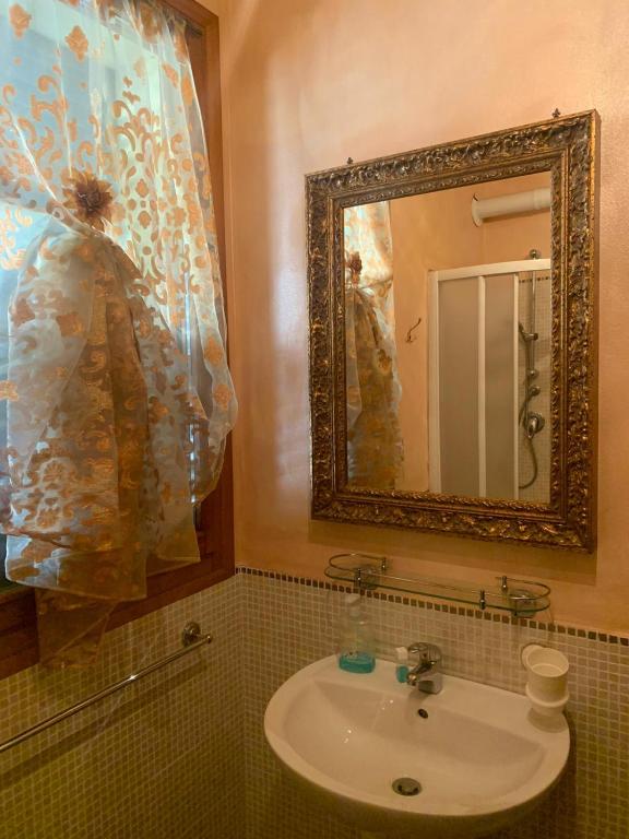 łazienka z umywalką i lustrem w obiekcie B&B Dal Fiocinino w mieście Comacchio